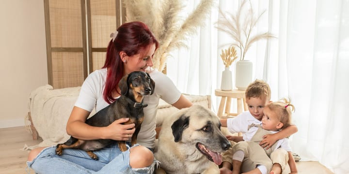 Mutter sitzt mit Dackel auf dem Schoß im Atelier, daneben ein großer Hund und zwei kleine Geschwister
