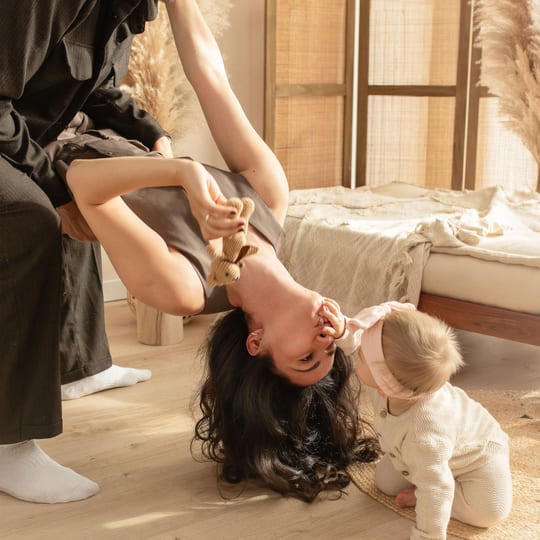 Mutter hängt kopfüber, ihre kleine Tochter krabbelt neben ihr auf dem Boden