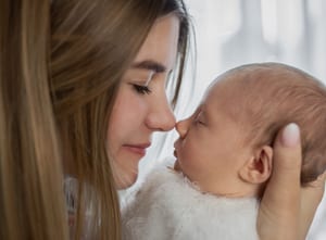 Mutter berührt mit der Nase zärtlich die Nase ihres Neugeborenen